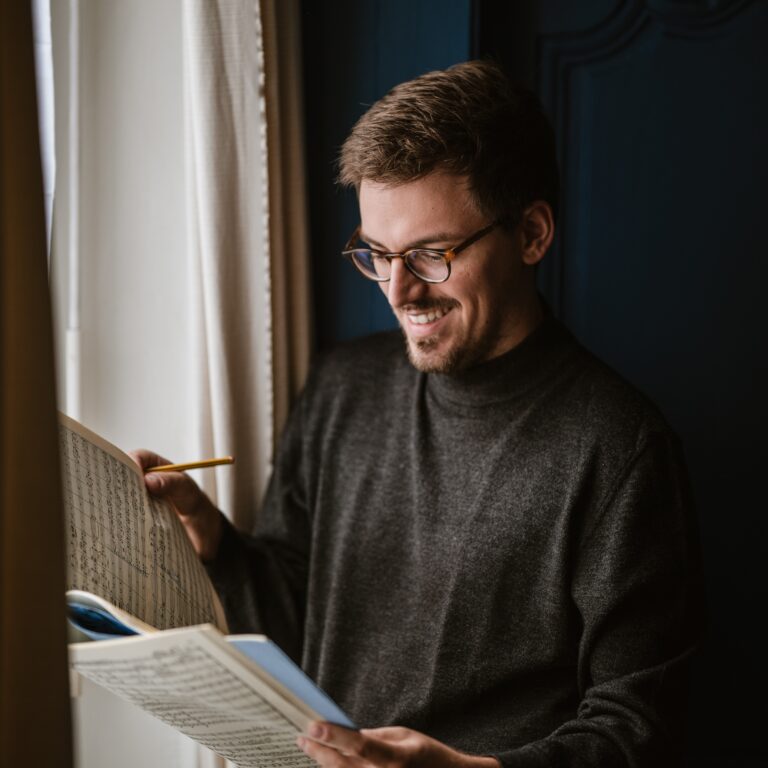 homme souriant regarde une partition musicale